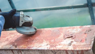 Bir adam tahtayı öğütüyor. Tahtalardan eski boyaları çıkarıyorum. Marangozluk işi. seçici odak