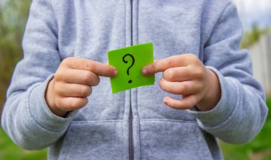 Çocuğun elinde parkın arka planında soru işareti olan çıkartmalar var. Doğa. seçici odak