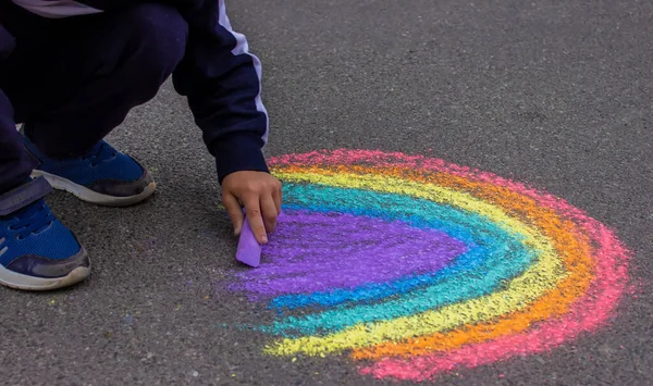 draws a rainbow, sun, car with chalk on the asphalt. Selective focus