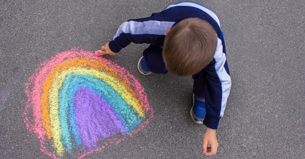 draws a rainbow, sun, car with chalk on the asphalt. Selective focus