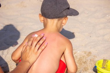 Annem Sin 'in sırtına kalp şeklinde güneş kremi sürüyor. seçici odak