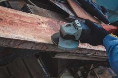 Bir adam tahtayı öğütüyor. Tahtalardan eski boyaları çıkarıyorum. Marangozluk işi. seçici odak