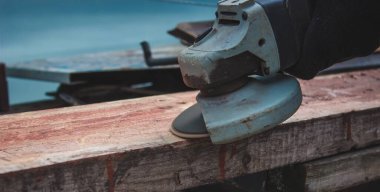 Bir adam tahtayı öğütüyor. Tahtalardan eski boyaları çıkarıyorum. Marangozluk işi. seçici odak