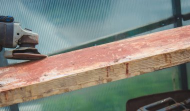 Bir adam tahtayı öğütüyor. Tahtalardan eski boyaları çıkarıyorum. Marangozluk işi. seçici odak