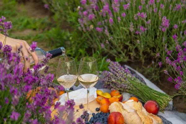 A bottle of wine on a background of a lavender field. Glasses with wine, fruits. selective focus