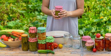 A woman preserves vegetables in jars. Selective focus. Food.