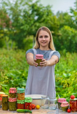 A woman preserves vegetables in jars. Selective focus. Food.