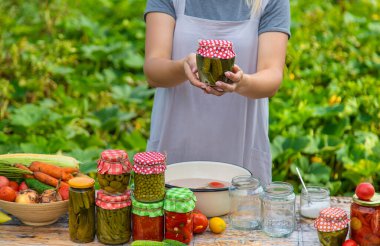 A woman preserves vegetables in jars. Selective focus. Food.