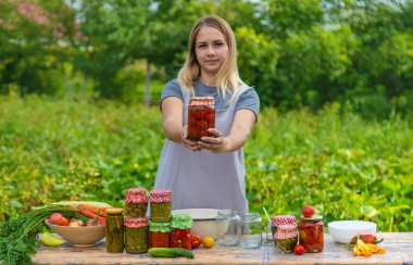 A woman preserves vegetables in jars. Selective focus. Food.
