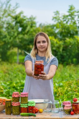 A woman preserves vegetables in jars. Selective focus. Food.