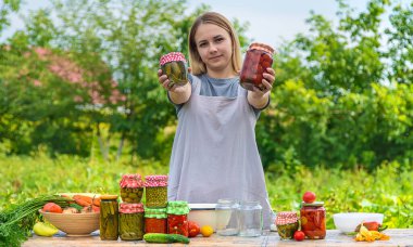 A woman preserves vegetables in jars. Selective focus. Food.