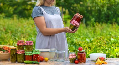 A woman preserves vegetables in jars. Selective focus. Food.