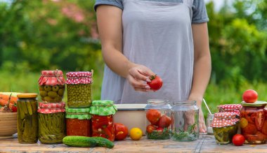 A woman preserves vegetables in jars. Selective focus. Food.