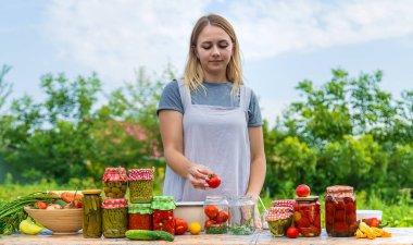 A woman preserves vegetables in jars. Selective focus. Food.