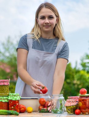 A woman preserves vegetables in jars. Selective focus. Food.