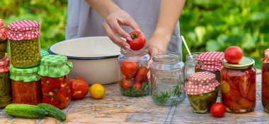 A woman preserves vegetables in jars. Selective focus. Food.