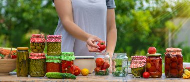 A woman preserves vegetables in jars. Selective focus. Food.