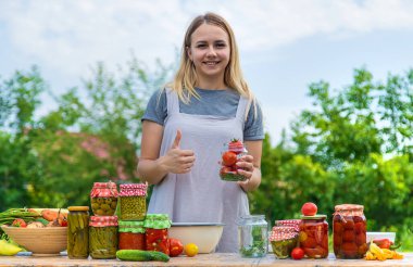 A woman preserves vegetables in jars. Selective focus. Food.