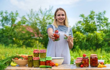 A woman preserves vegetables in jars. Selective focus. Food.