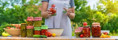 A woman preserves vegetables in jars. Selective focus. Food.