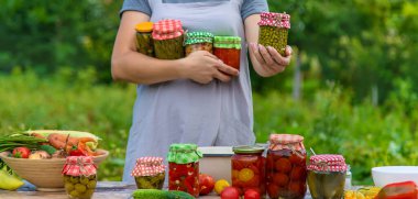 A woman preserves vegetables in jars. Selective focus. Food.