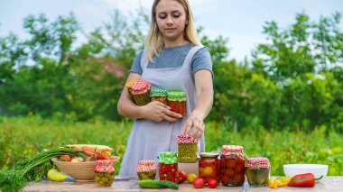 A woman preserves vegetables in jars. Selective focus. Food.