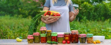 A woman preserves vegetables in jars. Selective focus. Food.