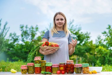 A woman preserves vegetables in jars. Selective focus. Food.
