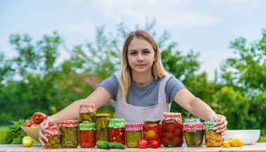 A woman preserves vegetables in jars. Selective focus. Food.
