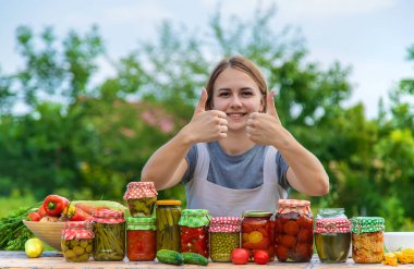 A woman preserves vegetables in jars. Selective focus. Food.