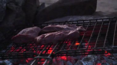 Game meat being roasted on a barbecue on open fire
