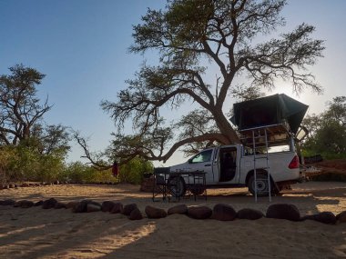 white 4x4 pick up with canopy and roof top tent camping on a road trip standing in the arid desert landscape of Namibia