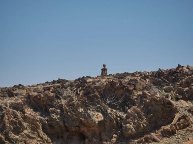 Kaokoveld, Namibia - 11 03 2016: Lone man rock sculpture sitting on the side of the road in Nambia