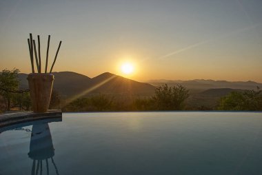 Romantik güneş Namibya 'da sonsuz bir havuzun üzerinde batıyor.