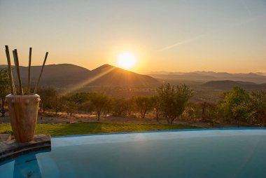 Romantik güneş Namibya 'da sonsuz bir havuzun üzerinde batıyor.