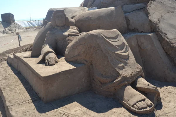 sand sculpture of woman who is resting lying on her back