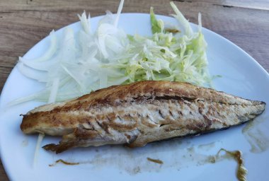 Tabakta biraz marul ve ızgara balık.