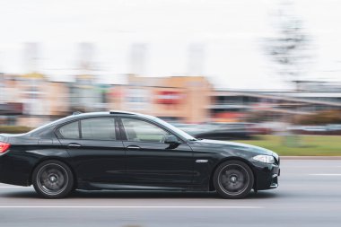 Araba yolda yüksek hızda seyahat ediyor. BMW 5 serisi trafikte. Hareket bulanıklığı. Riga, Letonya - 30 Sep 2021.