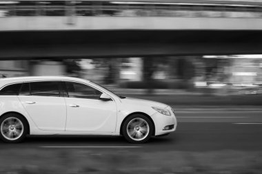 Beyaz Opel Insignia caddede son sürat ilerliyor. Hareket bulanıklığı. Riga, Letonya - 02 Ekim 2021.