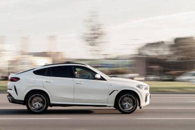 Beyaz BMW X6 yolda ilerliyor. Hızlı hareket eden araba. Hareket bulanıklığı. Riga, Letonya - 06 Ekim 2021.
