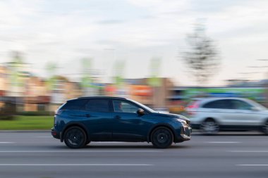 Mavi bir araba asfalt yolda gidiyor. Peugeot 3008. Hareket bulanıklığı. Riga, Letonya - 07 Ekim 2021