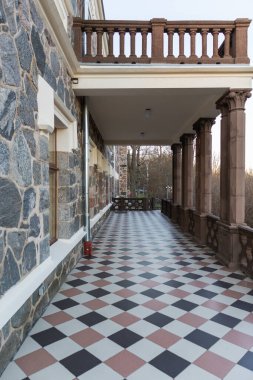 Terası ve sütunları olan eski bir taş evin manzarası.