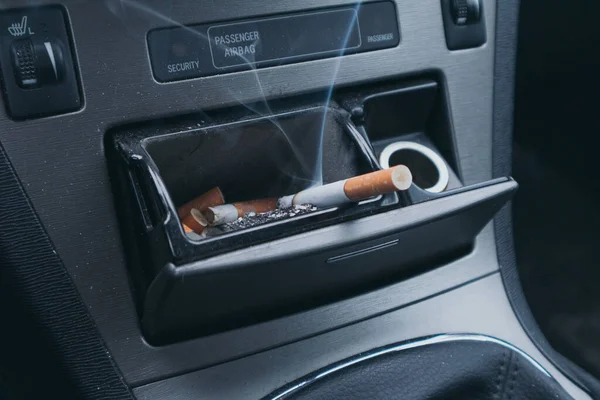 車の灰皿の中でタバコを蒸す 車内での喫煙 — ストック写真