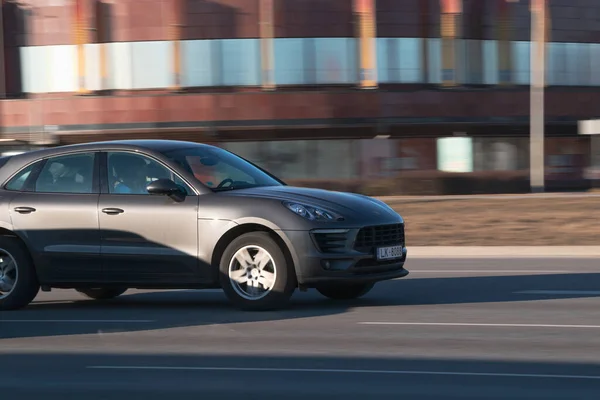Porsche Macan caddede son sürat gidiyor. Caddedeki bir arabanın yakın çekimi. Riga, Letonya - 16 Mar 2022