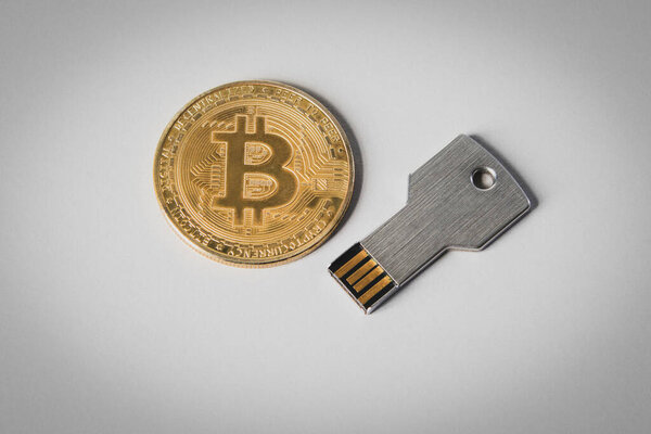 Bitkoin coin and usb memory card on a white background. Cryptocurrency storage.