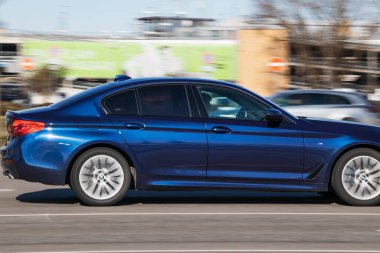 BMW 5 serisi sokakta. Yolda mavi yüksek hızlı araba Riga, Letonya - 31 Mar 2022.