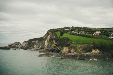 Okyanus kıyısındaki tepedeki villalar. Kayalık bir deniz kıyısında yaşıyor