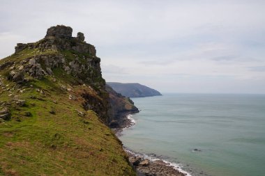 Büyük dağlar, okyanus kıyısındaki kayalıklar. Bulutlu havada dumanlı okyanus. Lynmouth, Devon, İngiltere, İngiltere.