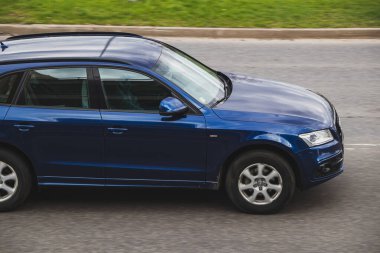 Mavi araba asfalt bir sokakta sürüyor. Yan görüntüyü yakından çek. Audi Q5. Riga, Letonya - 28 Nisan 2022.