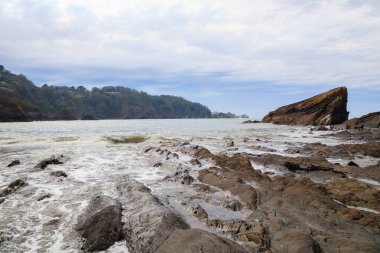 Fırtınadan önce bulutlu havada kayalıkları olan okyanus kıyısı..